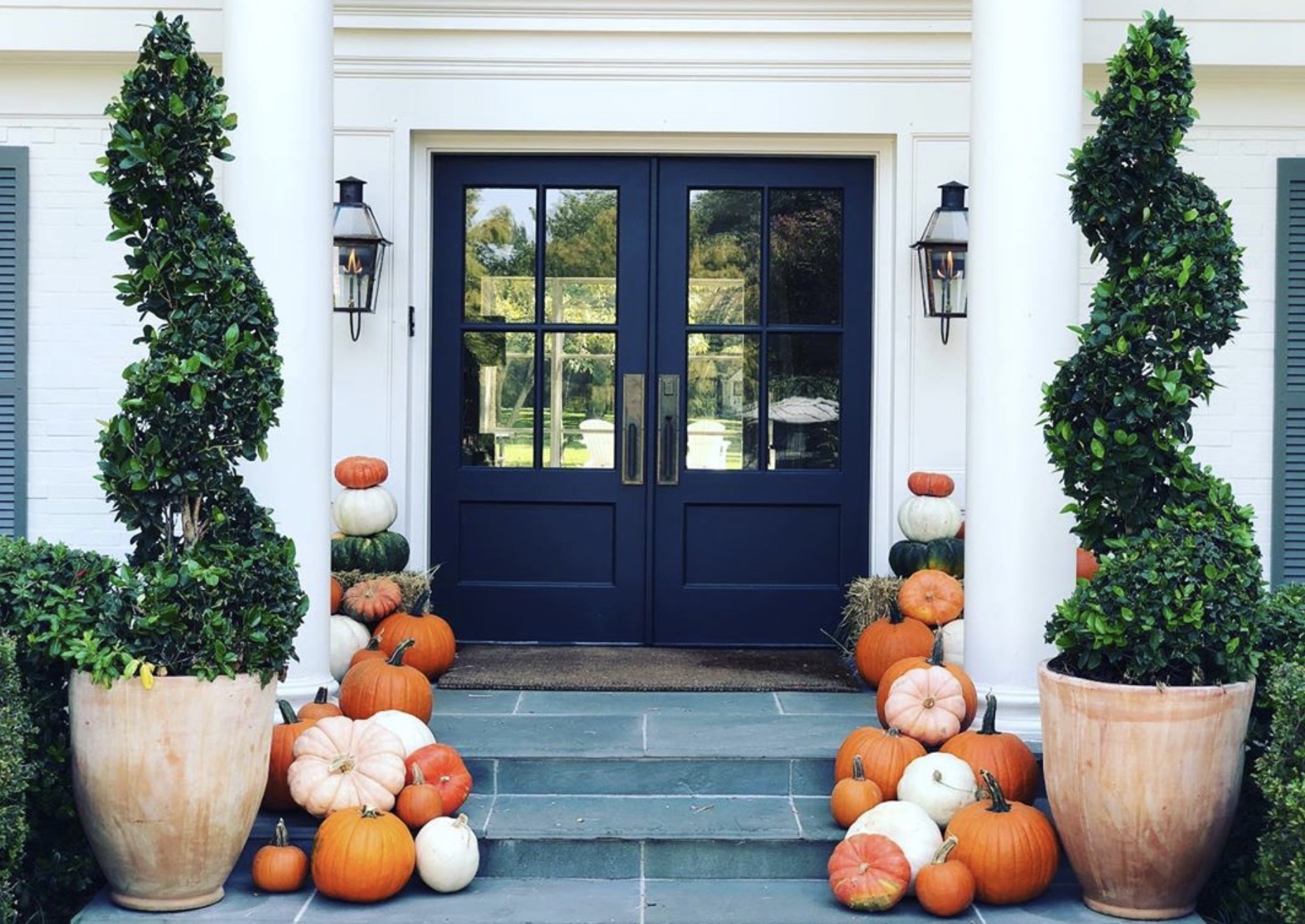 Classic front porch decorated with an abundant display of orange and white pumpkins