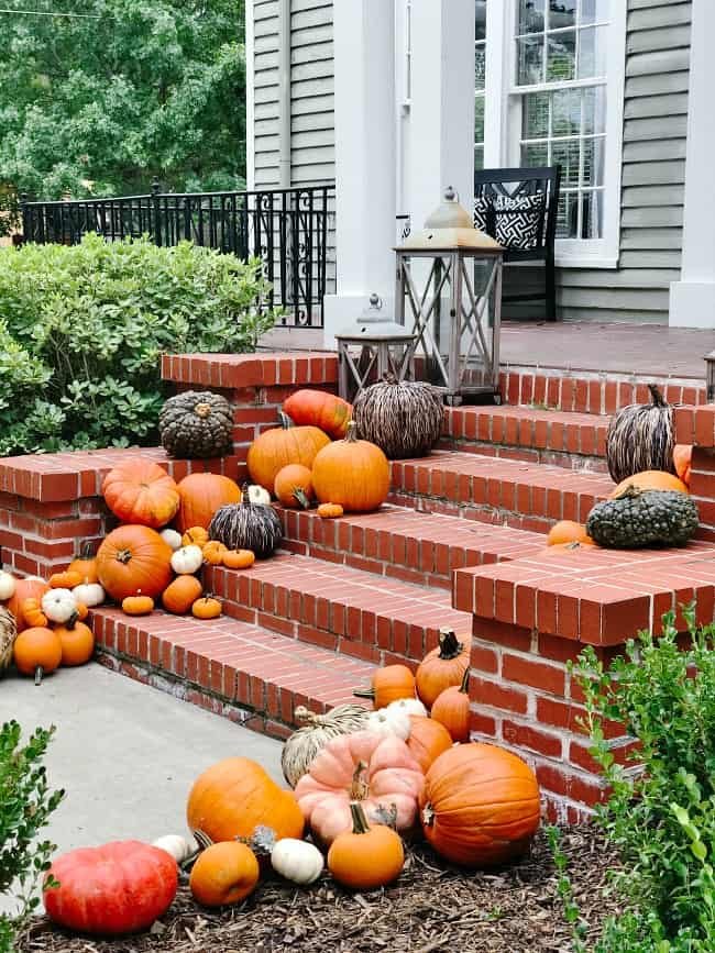 A welcoming porch dressed for fall with pumpkins and seasonal greenery
