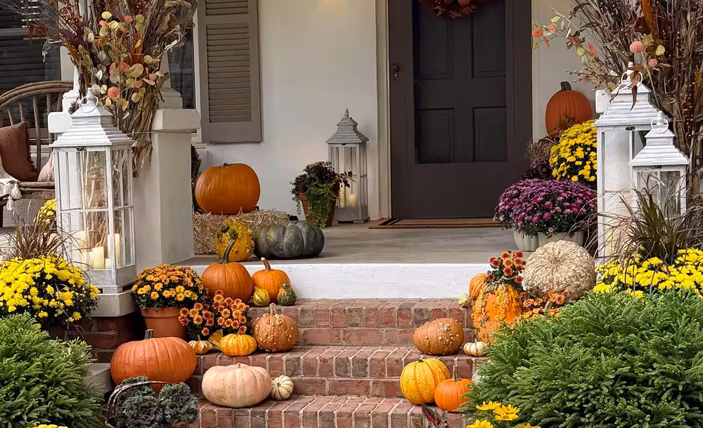 Seasonal porch entry decorated with pumpkins and mums